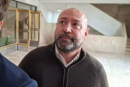 Un hombre adulto con barba está de pie en el interior de un edificio.