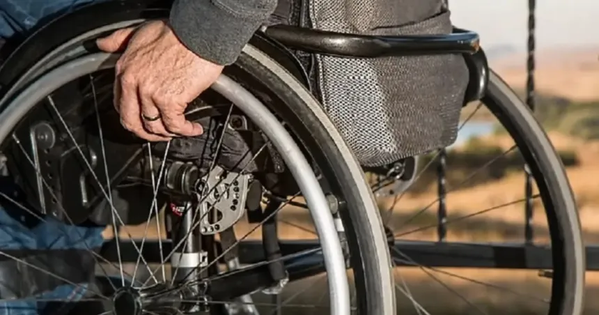 Una persona en silla de ruedas apoya la mano sobre una de las ruedas.