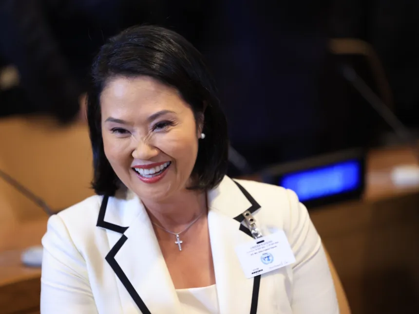 Keiko Fujimori sonríe durante un evento con un saco blanco.