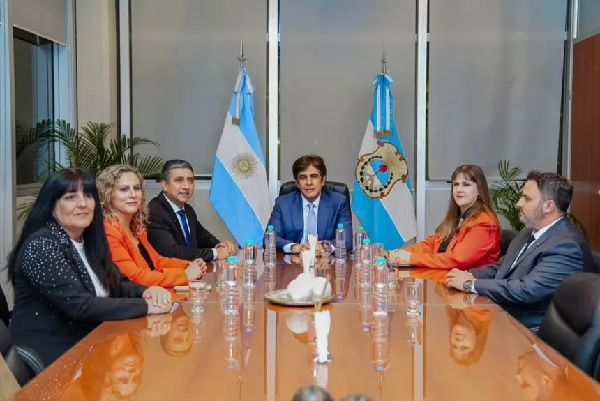 Funcionarios reunidos alrededor de una mesa, con las banderas argentina y de San Juan al fondo.