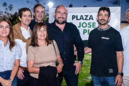 Adultos posan frente al cartel de la Plaza José de la Plata.