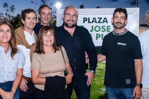 Adultos posan frente al cartel de la Plaza José de la Plata.