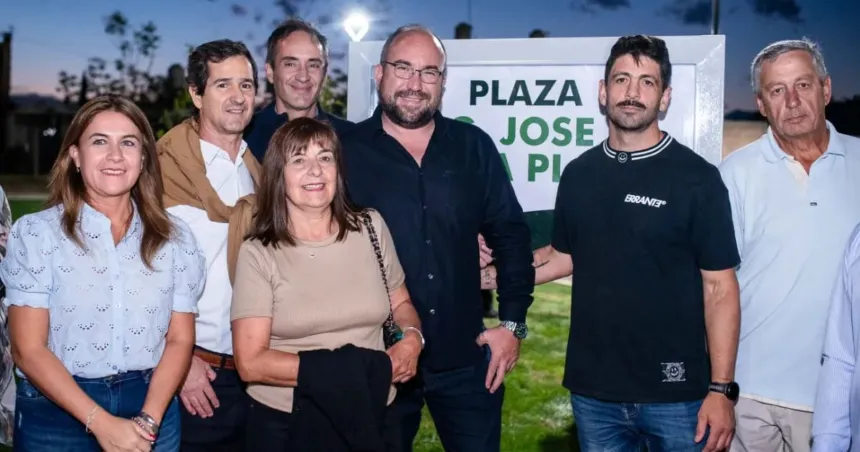 Adultos posan frente al cartel de la Plaza José de la Plata.