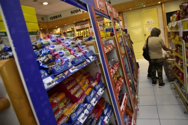 Una mujer adulta recorre los pasillos de un almacén con productos en los estantes.