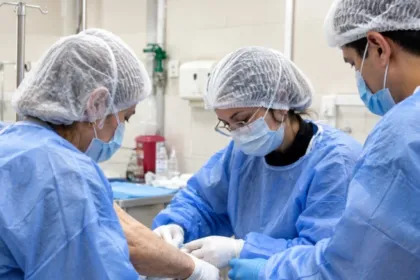 Personal de salud atiende el brazo de un paciente en una sala hospitalaria.