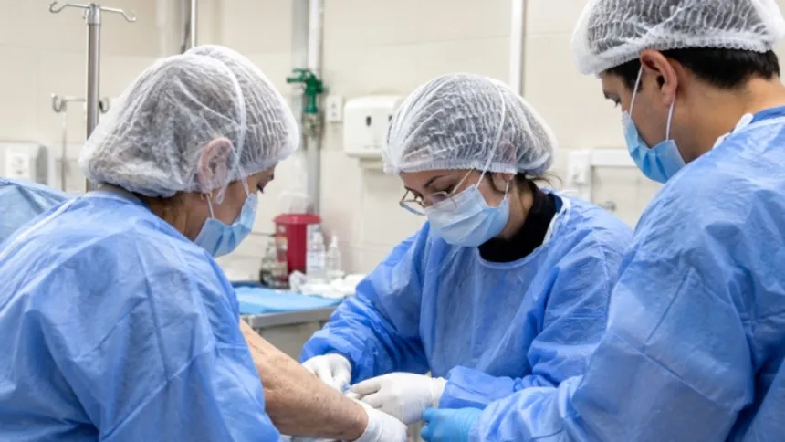 Personal de salud atiende el brazo de un paciente en una sala hospitalaria.