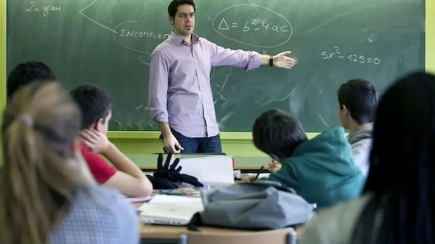 Un docente enseña Matemática frente al pizarrón a un grupo de estudiantes.
