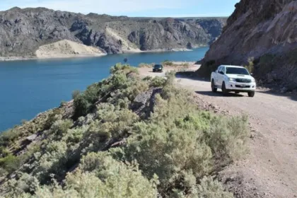 Ruta de ripio junto al agua en el Cañón del Atuel, con dos camionetas.