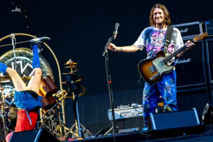 Red Hot Chili Peppers en vivo: Flea hace una vertical junto a la batería mientras John Frusciante toca la guitarra.