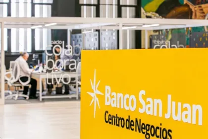 Cartel de Banco San Juan en un centro de negocios, con una persona trabajando al fondo.