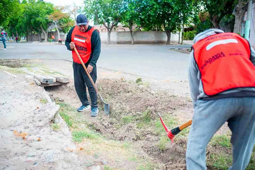 Trabajadores municipales despejan una zanja junto a la calle.