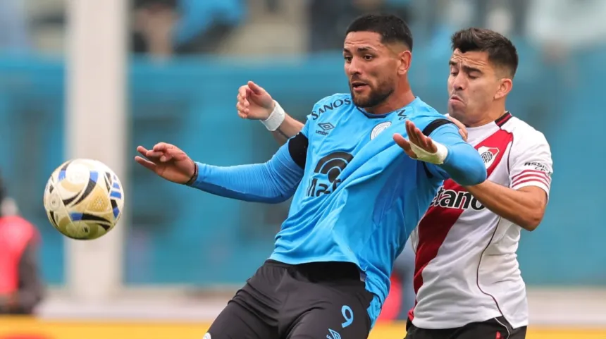 Un jugador de Belgrano disputa la pelota con un futbolista de River.
