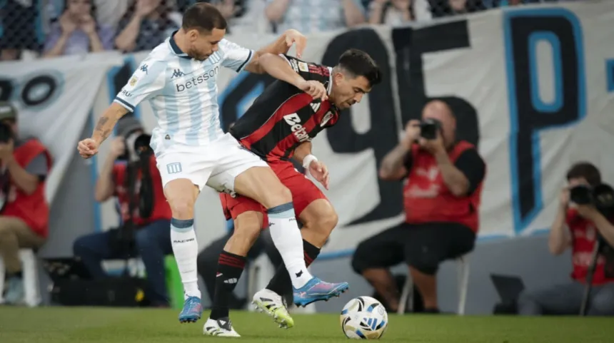 Un jugador de Racing y otro de River disputan la pelota en el campo.
