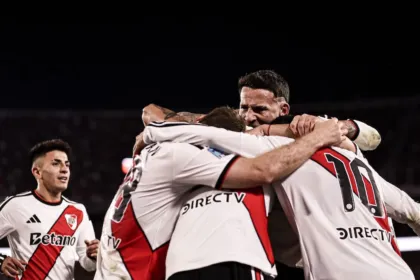 Futbolistas de River Plate se abrazan para celebrar en la cancha.