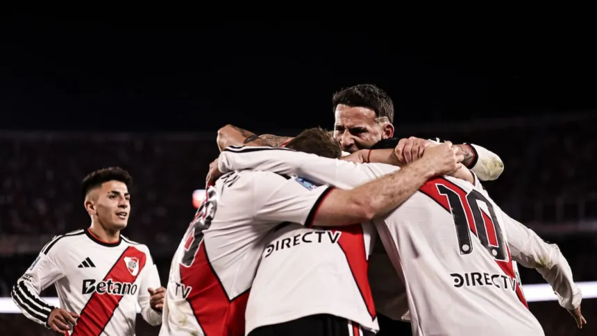 Futbolistas de River Plate se abrazan para celebrar en la cancha.
