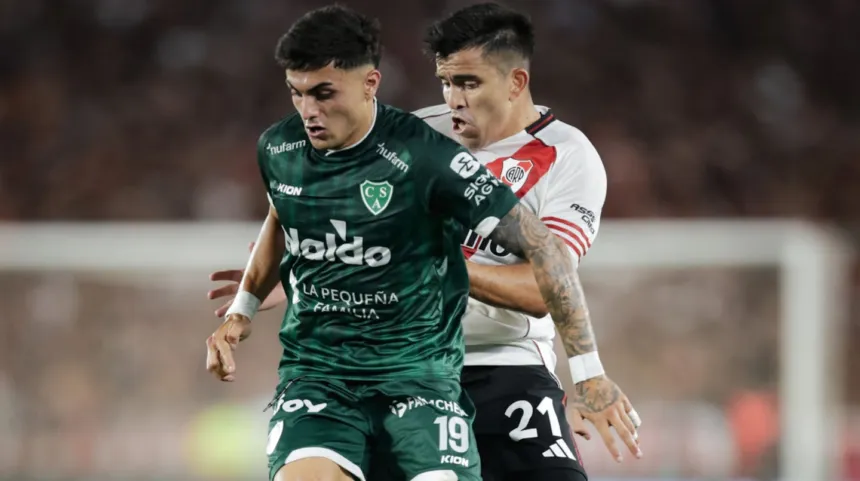 Un jugador de Sarmiento disputa la pelota con un futbolista de River Plate.