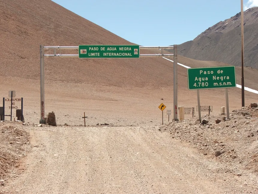 Carteles señalizan el Paso de Agua Negra en un camino de montaña seco y despejado.
