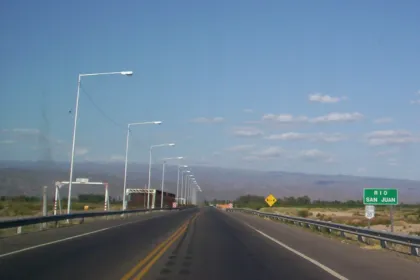 Ruta asfaltada con carteles viales y paisaje árido junto al Río San Juan.