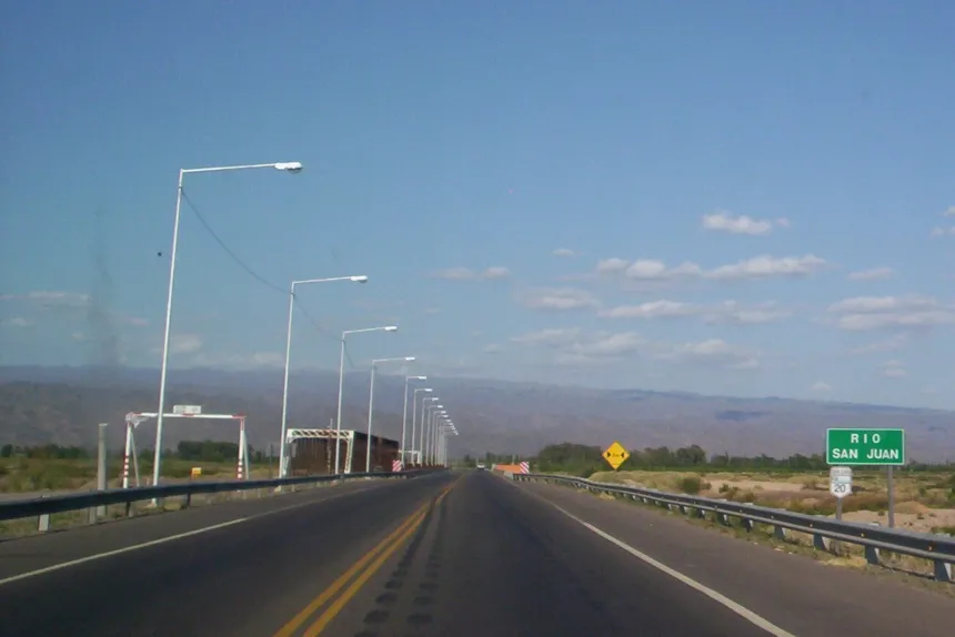 Ruta asfaltada con carteles viales y paisaje árido junto al Río San Juan.