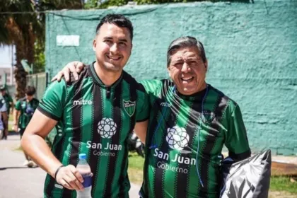 Dos hinchas adultos posan con camisetas verdes y negras de San Martín.