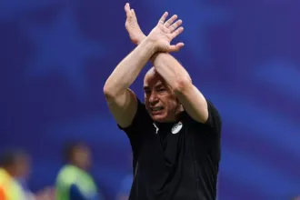 El entrenador de Egipto aplaude con la camiseta de la selección en un estadio.