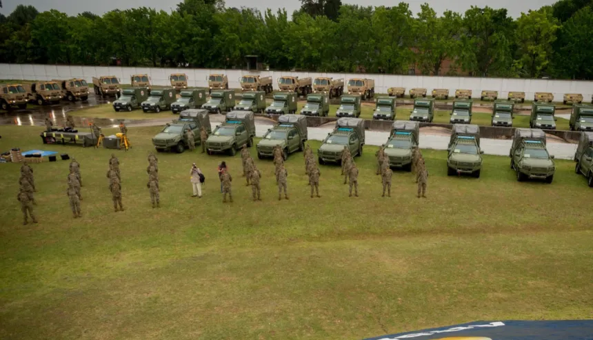 Vehículos militares y personal uniformado en formación en un predio