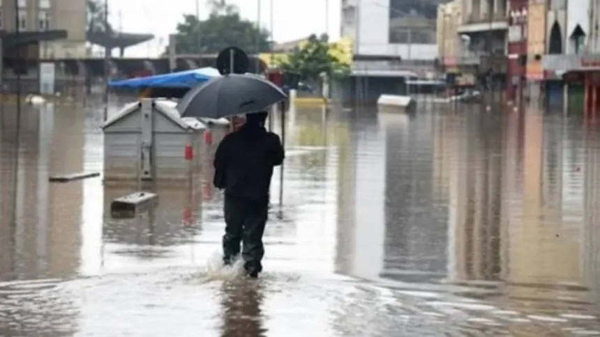 Una persona con paraguas camina por una calle inundada.