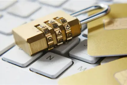 Candado sobre un teclado junto a tarjetas bancarias, en una imagen sobre seguridad digital.