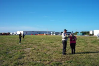 Predio de SpaceX con edificios al fondo y dos adultos en primer plano.