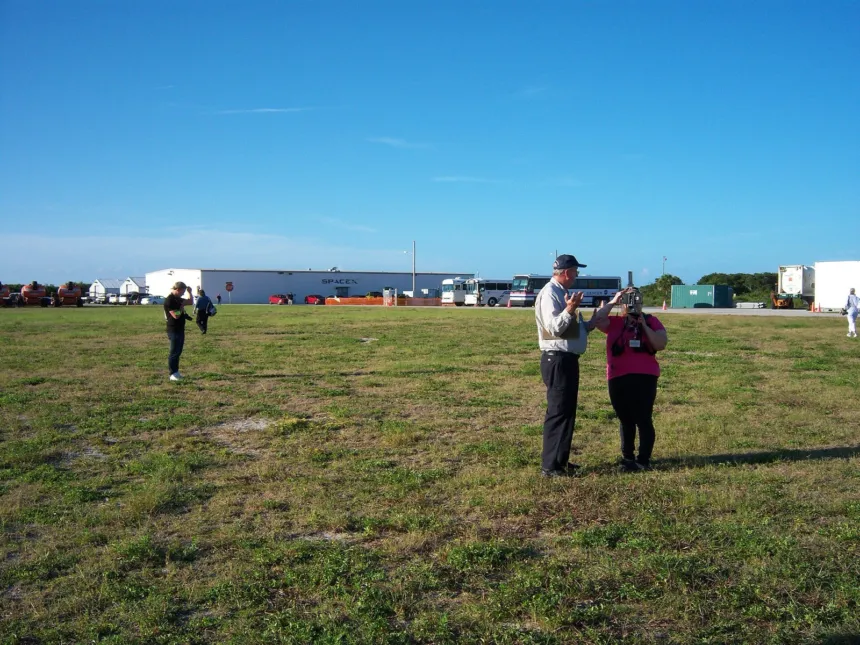 Predio de SpaceX con edificios al fondo y dos adultos en primer plano.
