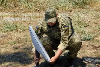 Un soldado ucraniano instala una antena de Starlink en el campo.