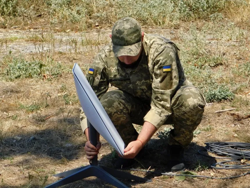 Un soldado ucraniano instala una antena de Starlink en el campo.