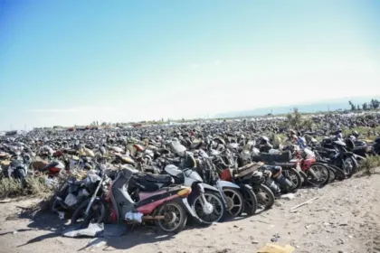 Numerosas motocicletas permanecen estacionadas en un depósito al aire libre.