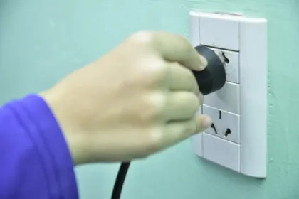 Una mano enchufa un aparato en la pared.