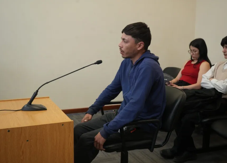 Un hombre declara sentado ante un micrófono en una sala de audiencias.
