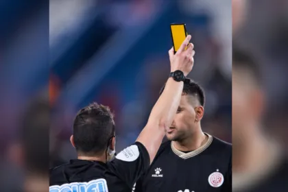 Un árbitro muestra una tarjeta virtual amarilla frente a un jugador.