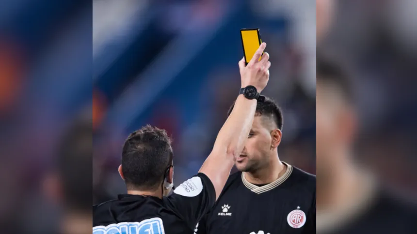 Un árbitro muestra una tarjeta virtual amarilla frente a un jugador.