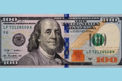 Billete de 100 dólares estadounidenses sobre un fondo celeste.