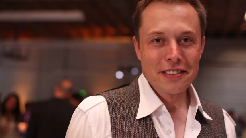 Elon Musk posa en un evento bajo techo.