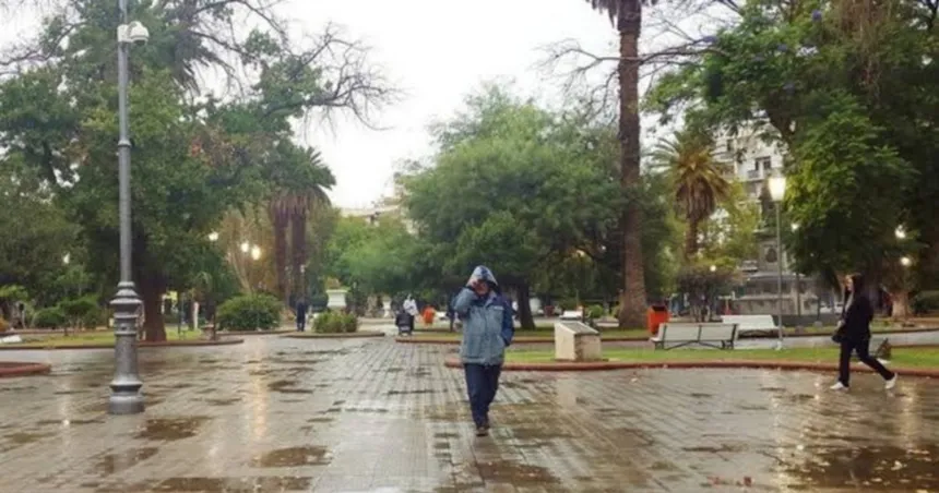 Una persona con capucha cruza la Plaza 25 de Mayo de San Juan en un día de lluvia.