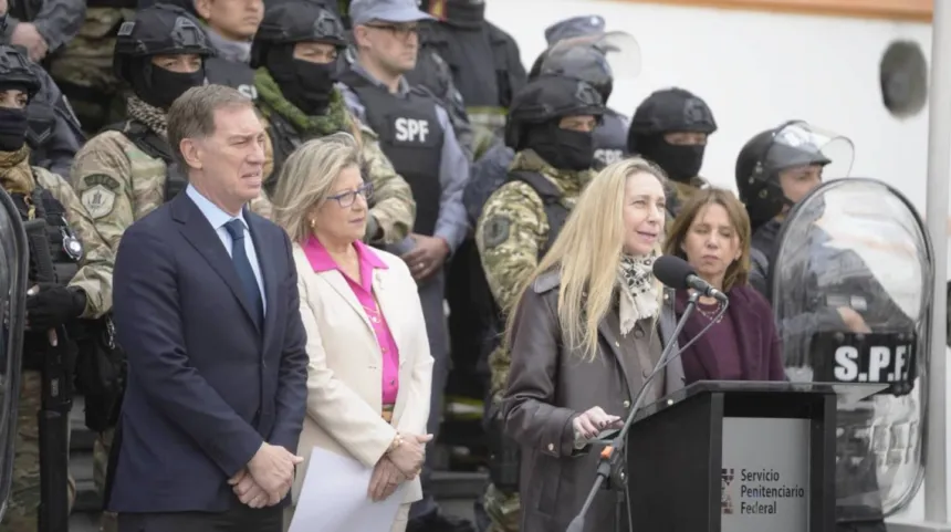 Una funcionaria habla ante un podio del Servicio Penitenciario Federal, rodeada de agentes