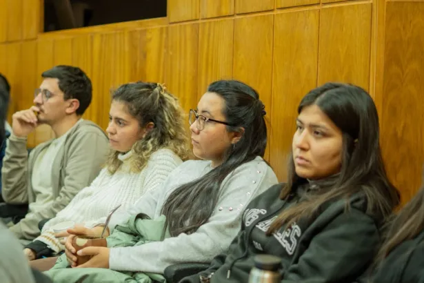 Estudiantes escuchan sentados durante una actividad en un salón.