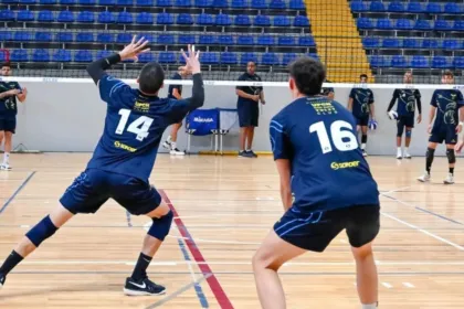 Jugadores de UPCN practican vóleibol en una cancha cubierta.