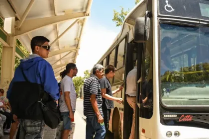 Pasajeros suben a un colectivo de RedTulum en una parada techada.