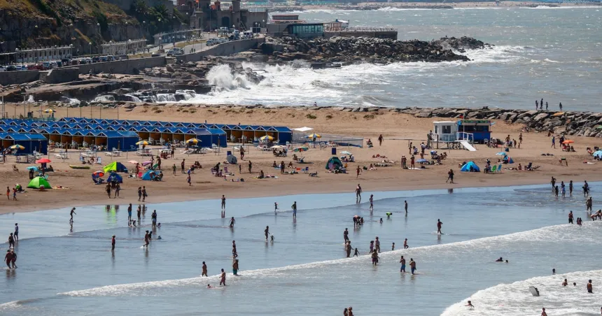 Personas disfrutan de una playa con sombrillas, carpas y olas.