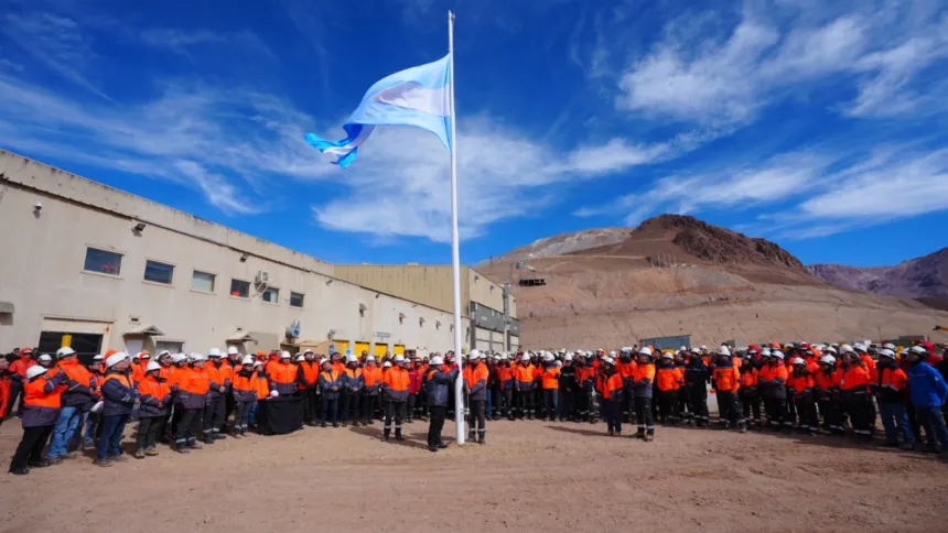 Trabajadores mineros con ropa de seguridad se reúnen frente a instalaciones de montaña.