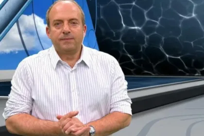 Fernando Confessore sentado en un estudio de televisión frente a pantallas meteorológicas.