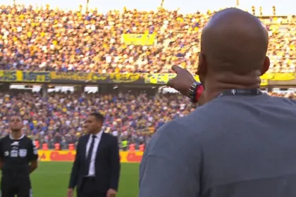 Un hombre señala hacia la tribuna durante un partido de fútbol.