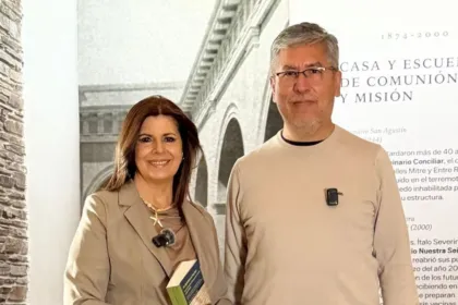 Una mujer y un hombre posan frente a un panel sobre la historia agustina.