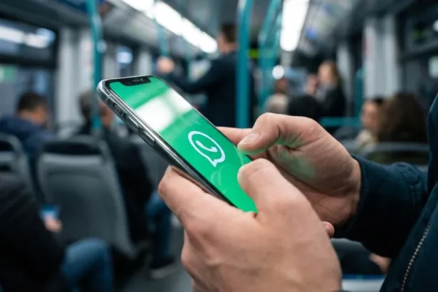 Una persona consulta WhatsApp en su celular durante un viaje en transporte público.